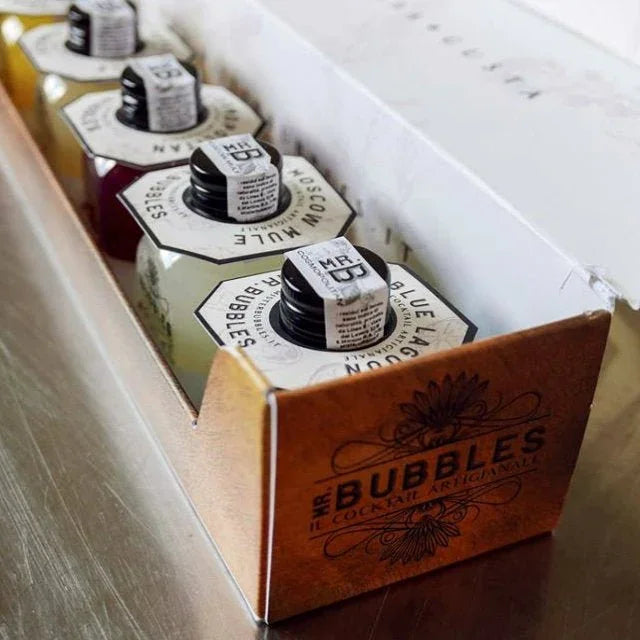 Confezione artigianale Mr. Bubbles con bottiglie di cocktail pronti su tavolo in acciaio