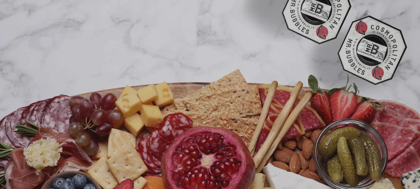 Tagliere gourmet con salumi, formaggi, cracker, frutta fresca, noci e cetriolini sottaceto su marmo bianco