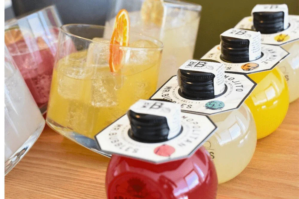 Cocktail monodose Mr. Bubbles con ghiaccio e fetta d'arancia su tavolo in legno