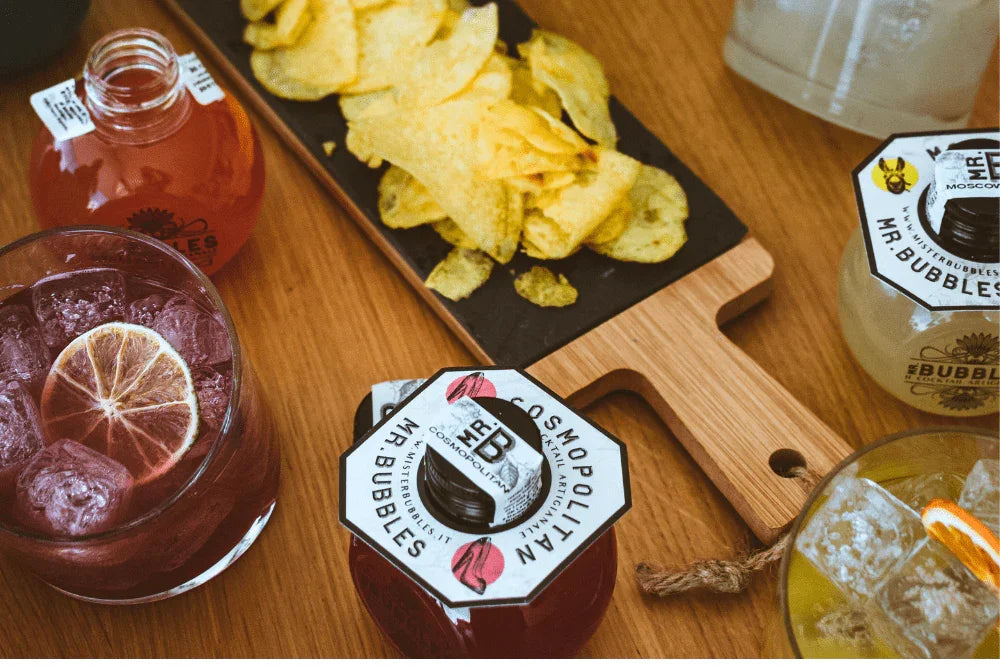 Cocktail pronti da bere Mr. Bubbles con chips su tagliere in legno su tavolo rustico