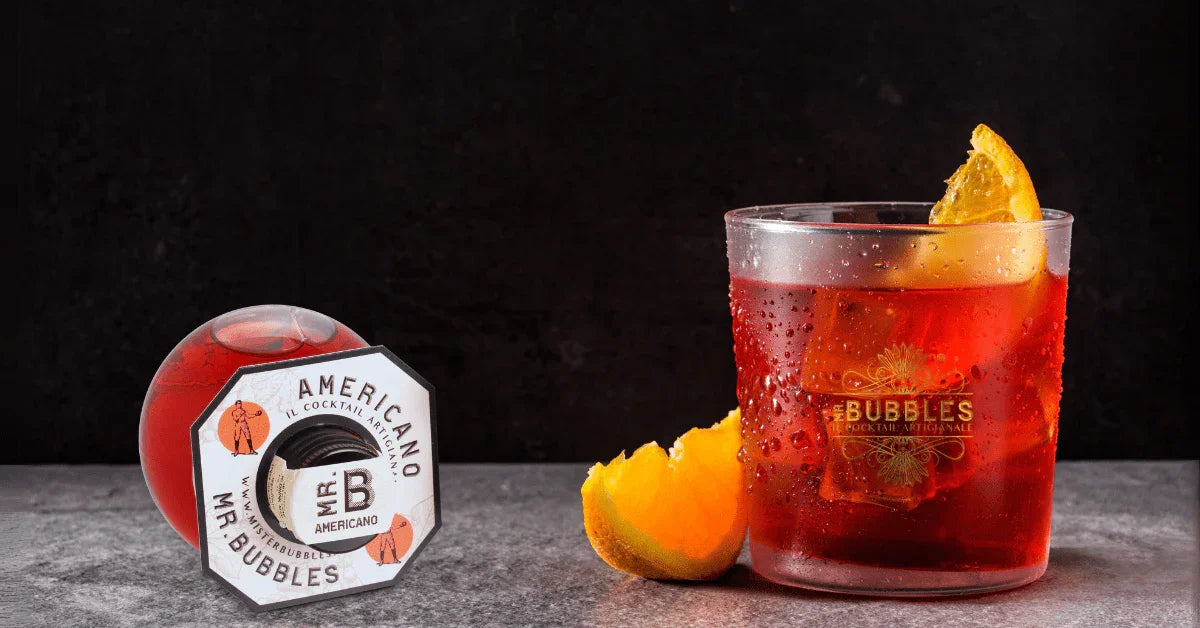 Cocktail Americano Mr. Bubbles in bicchiere con ghiaccio e fetta di arancia su sfondo scuro