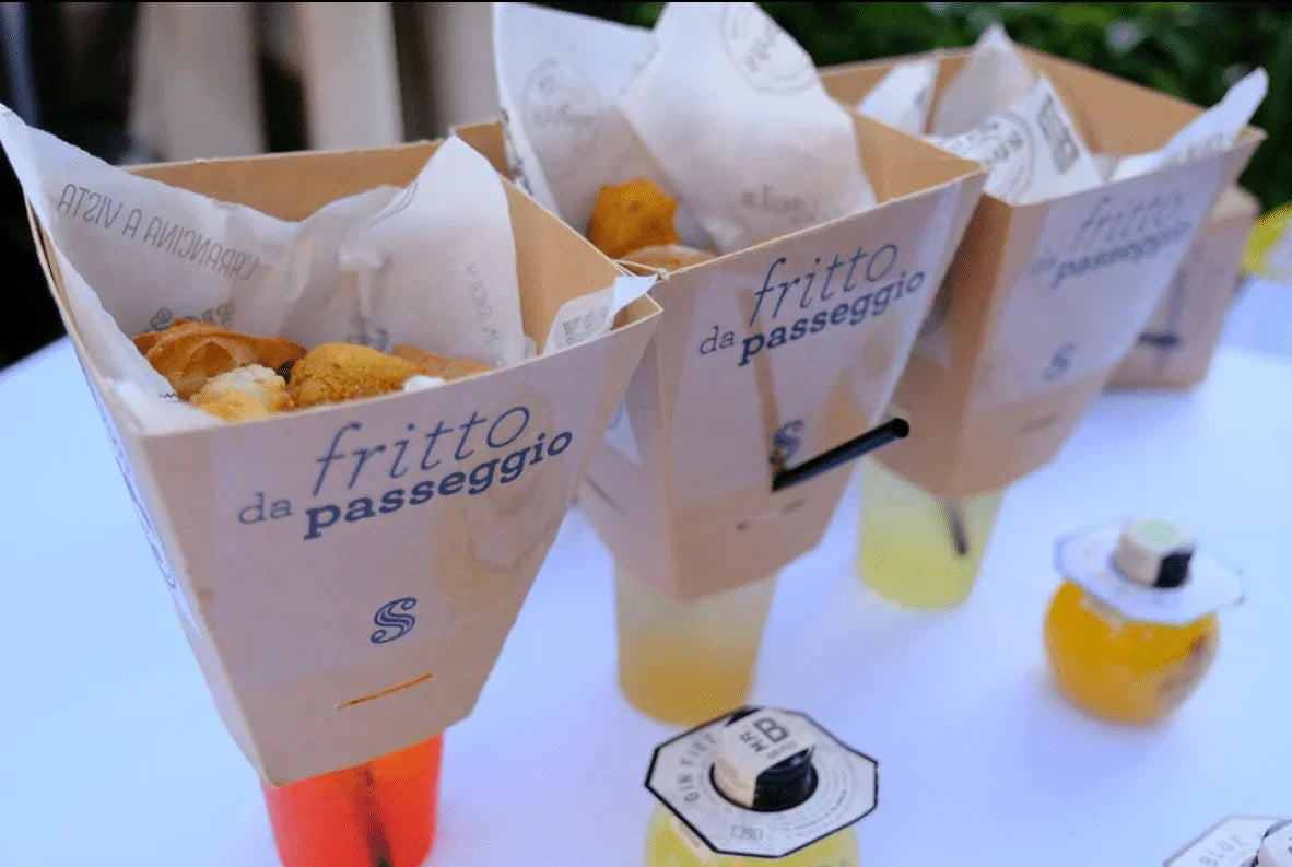 Porte-coni di fritto da passeggio con cibo fritto e bibite su tavolo bianco all'aperto